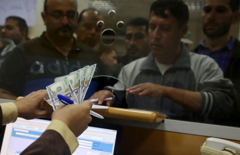 A man at a counter receives a handful of cash.