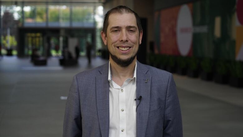 Portrait of a man in suit smiling inside the CBC/Radio-Canada building in Montreal. 