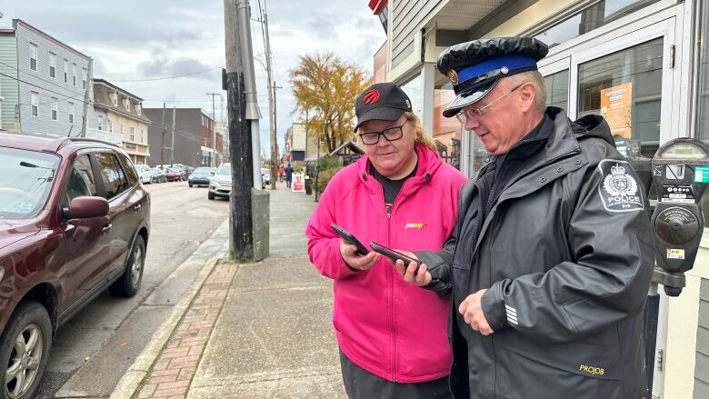 Theresa Rowe, area manager for Subway, and Cape Breton Regional Police Constable Gary Fraser use an app on their phones to communicate with other members of the Sydney downtown business watch group.