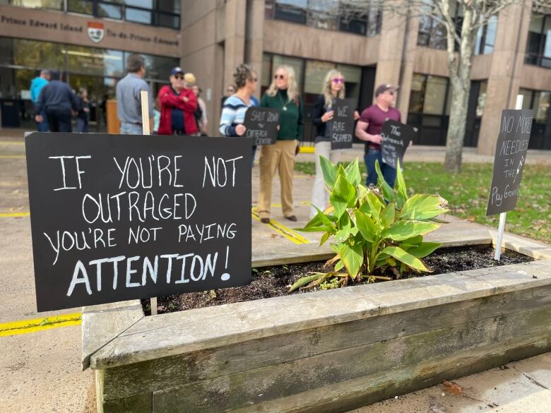 Signs attached to stakes are stuck inside a raised flower bed. 