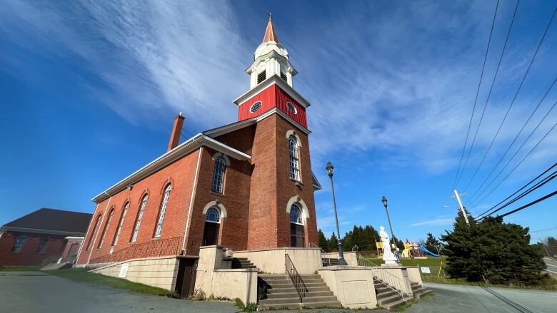 A brick church is seen against a blue sky.