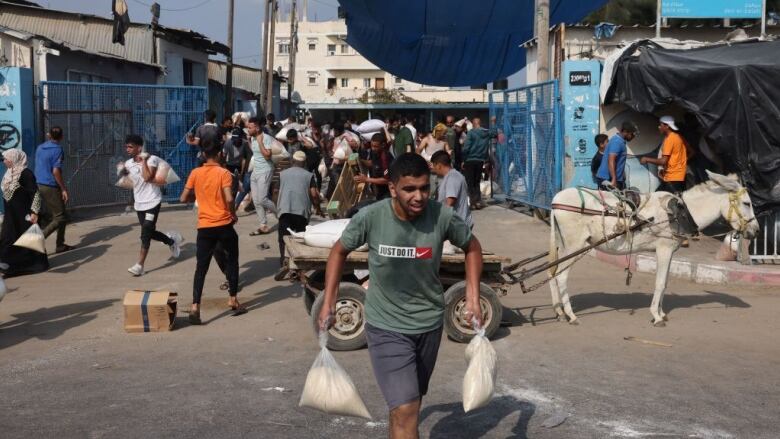 People walk from an aid distribution centre with bags of food.