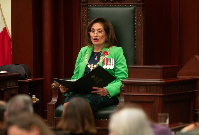 A woman sitting and reading out loud. 