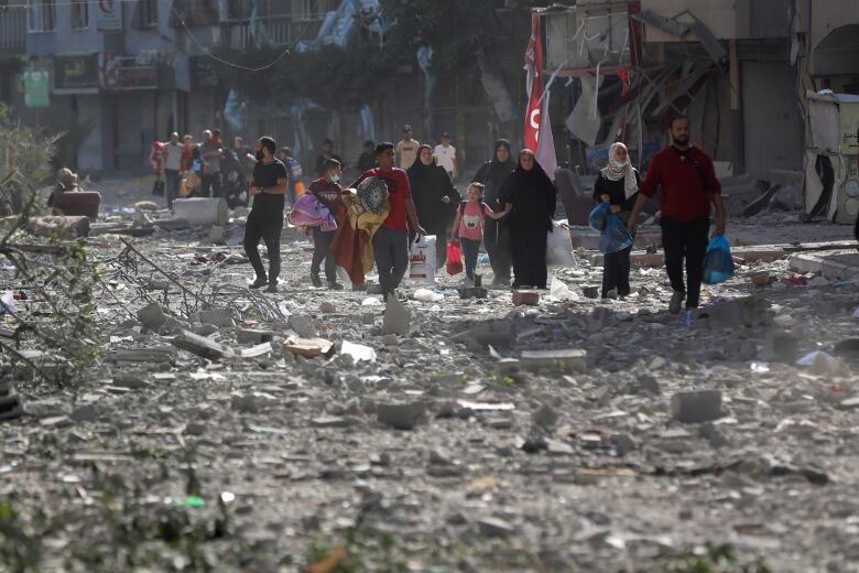 People walk through rubble after leaving their homes.