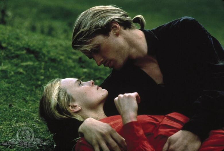 Robin Wright (right) and Cary Elwes (left) in The Princess Bride. They're laying on the grass looking at one another.