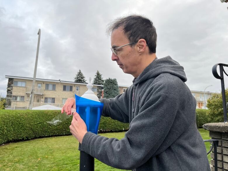 A man puts a blue filter over a light. 