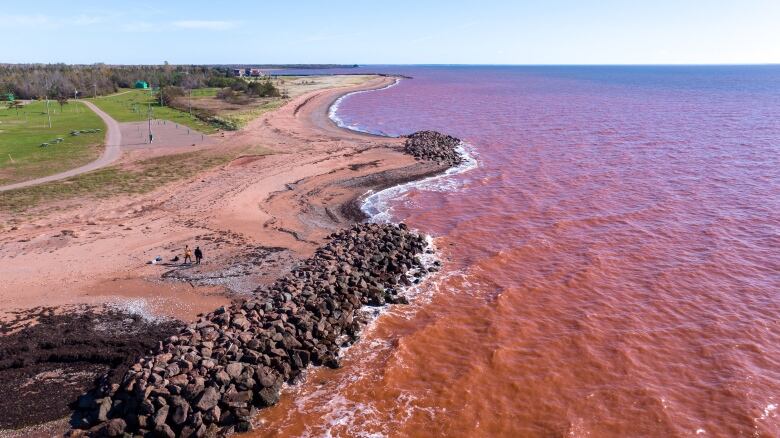 A drone view of two piles of rock on a shoreline 