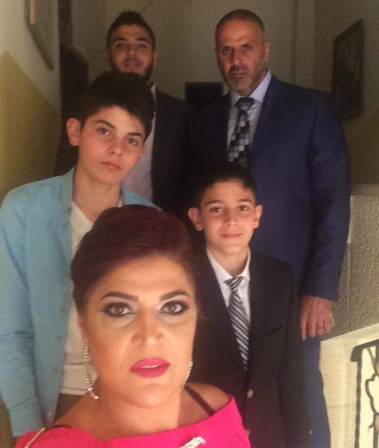 A woman stands with her children and husband on a stairwell. 