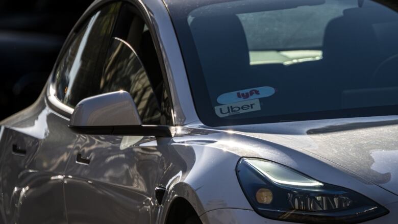 A car with an Uber and Lyft decal in its window is shown.