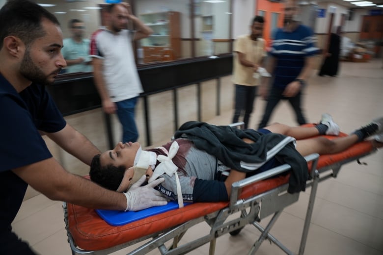 A paramedic transports an injured child on a gurney.