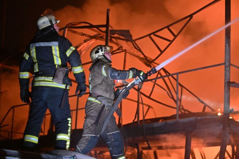 Two firefighters work to extinguish a blaze.