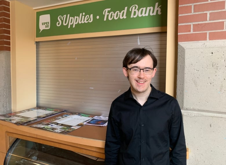 Man man with glasses standing in front of the food bank stand at UPEI.