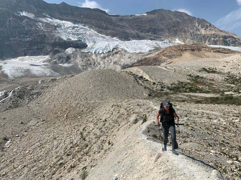 Kate Arpin stands on a pile of rocks in the mountains. 