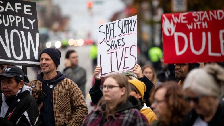 A crowd of people holding pro-safe supply signs.