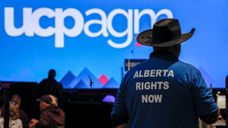 A man wearing a cowboy hat, wearing a shirt that reads 