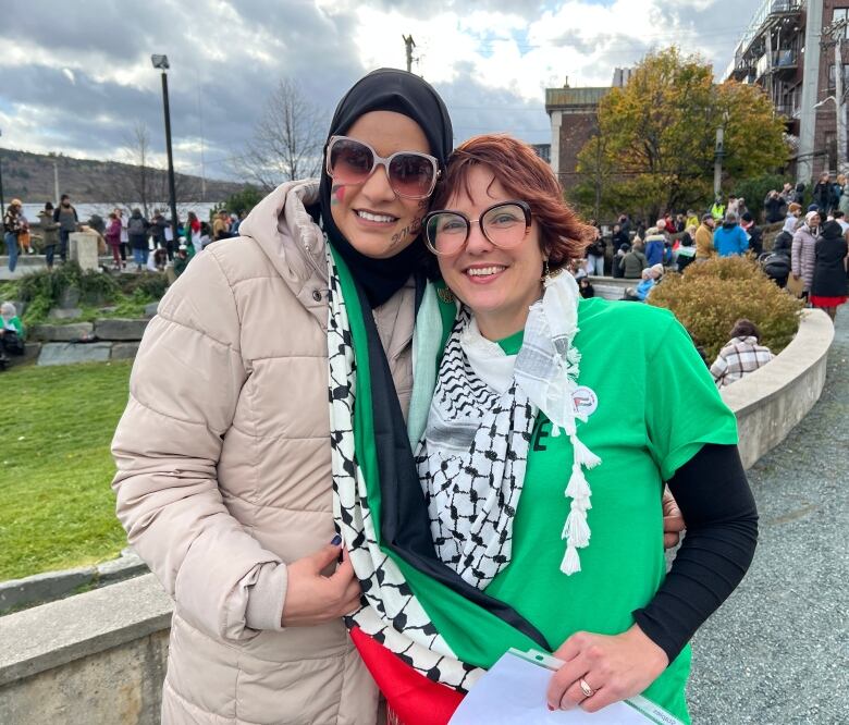 Two smiling women embrace.