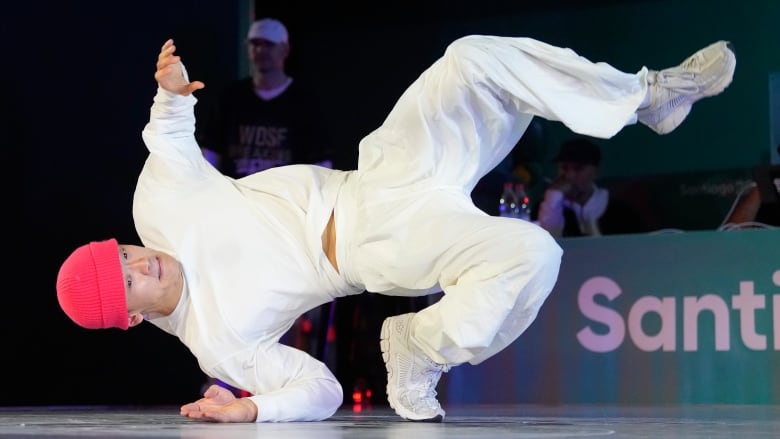 A male break dancer balances on his right arm and right foot during a competition.