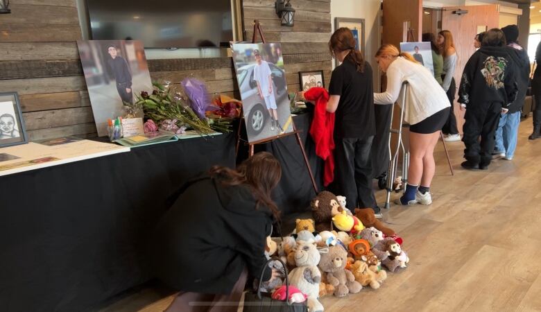 A memorial shows photos of Tristan and notebooks for people to leave notes on a table. 