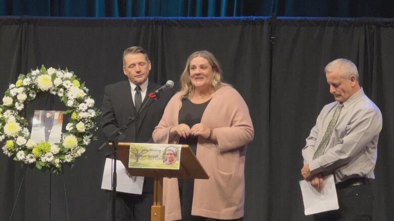 A mana nd woman stand on a stage in front of a podium.