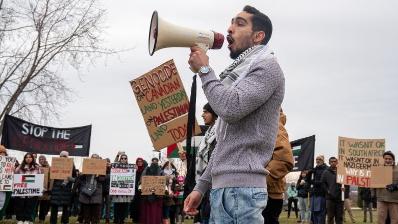 A man yells into a megaphone at a protest