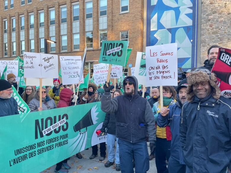 Demonstators hold signs at a protest outside Collge de Maisonneuve.