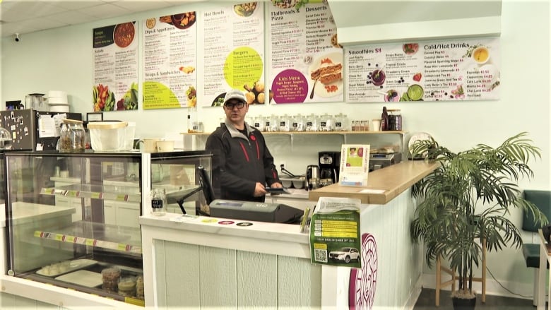 A man stands behind the counter at a restaurant.