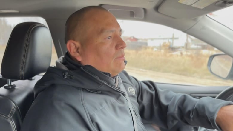 A man in a winter jacket at the wheel of a car