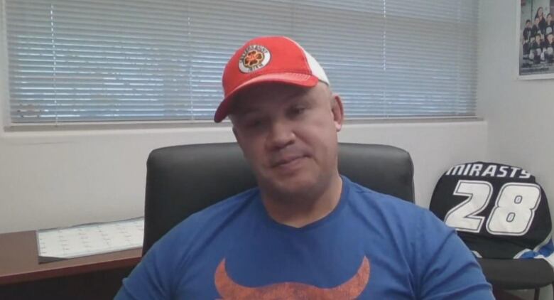 A man sits in an office with a hockey jersey laid over a chair in the background