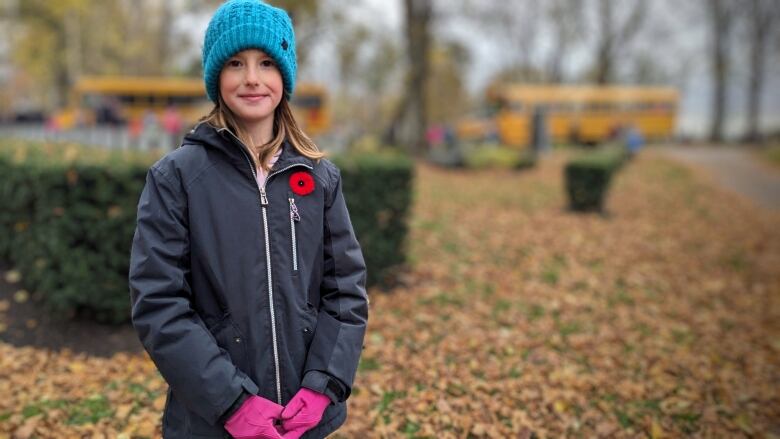 Girl in blue toque wearing poppy.