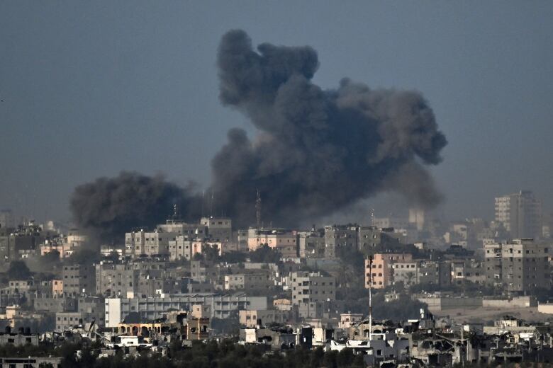 Black smoke billows from buildings following bombardment.