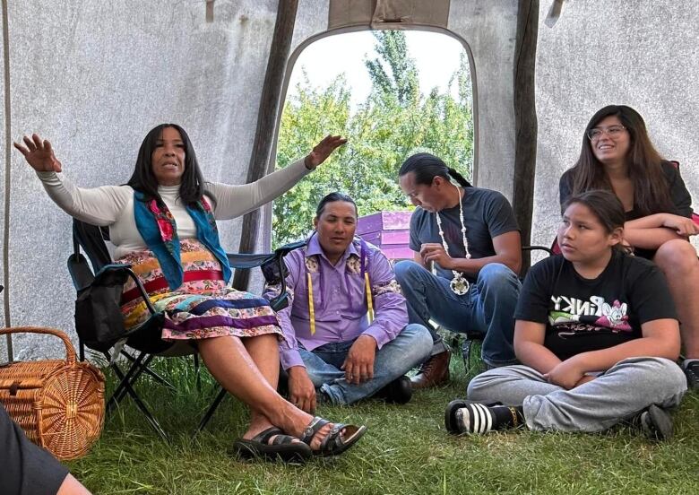 Youth and adults gather together inside a tipi.