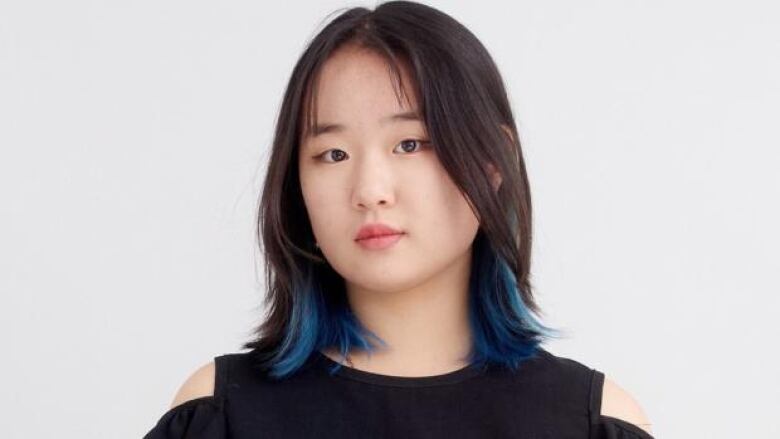 A young Asian girl with shoulder length dark hair with blue tips and wearing a black top