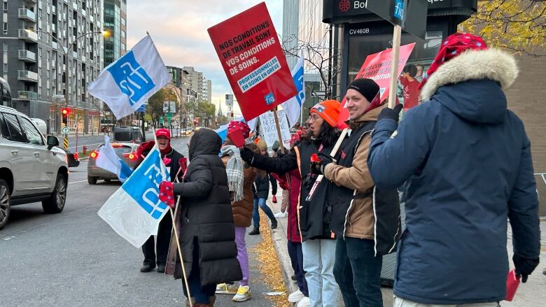 People holding signs on the side of the road during a strike.