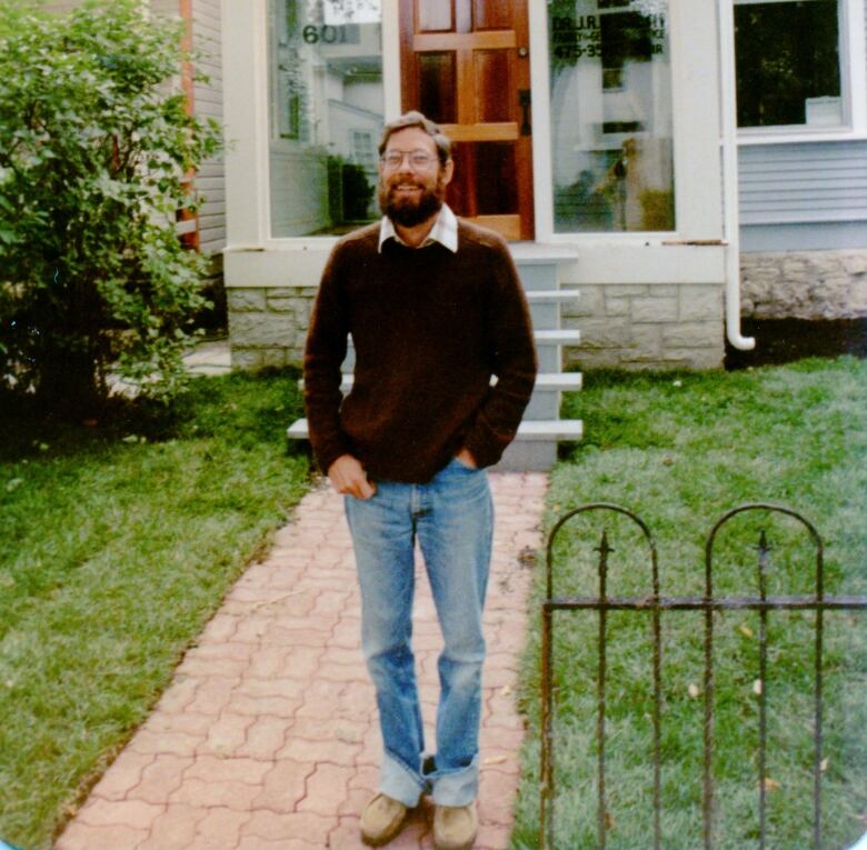 A man with a bead and glasses stands outside a medical clinic.