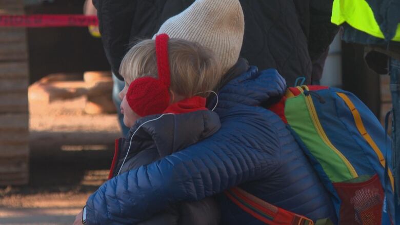 A woman hugs her young child. 