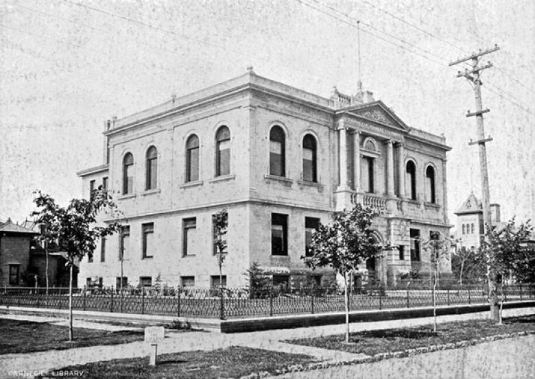 A black and white photo shows a large, ornate stone building.