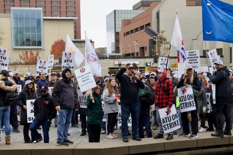 A crowd of workers hold picket signs and face toward the camera