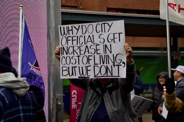 A person holds a sign reading: 