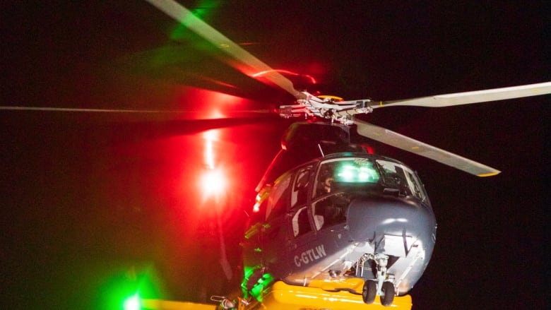 A helicopter flying at night drops water.