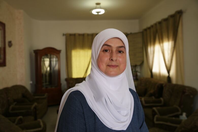 A woman in a white hajib stands in a living room