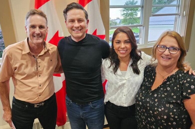 Two men and two women in casual clothing smile into the camera. 