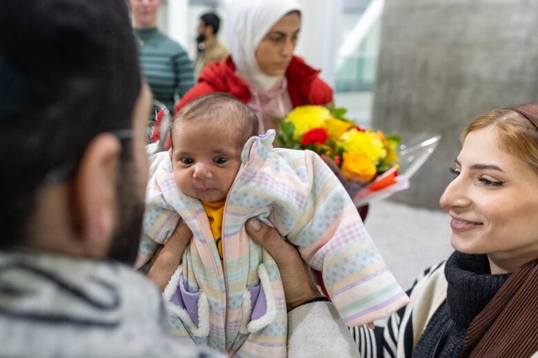 A baby is held up by someone whose back is to the camera.