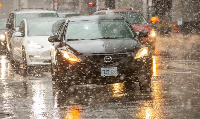 image of a car in driving on a Toronto street with show falling o