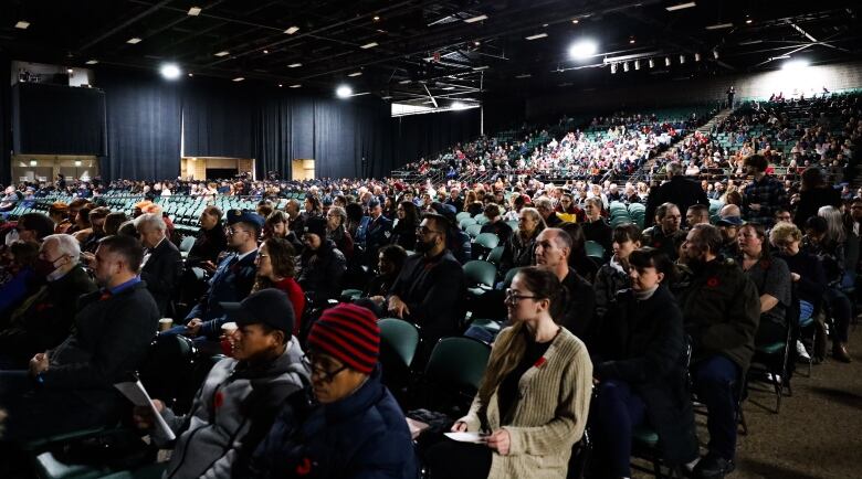 People sit in a crowd facing forward.