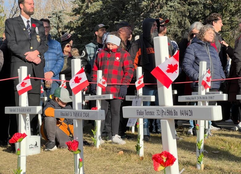 A crowd stands next to commemorative crosses at a Remembrance Day ceremony in Calgary.