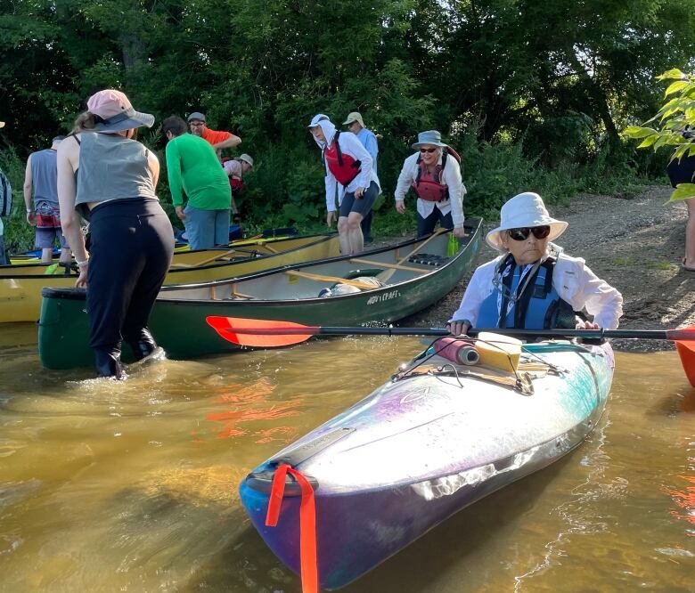 Several people sit in canoes on a sunny day.