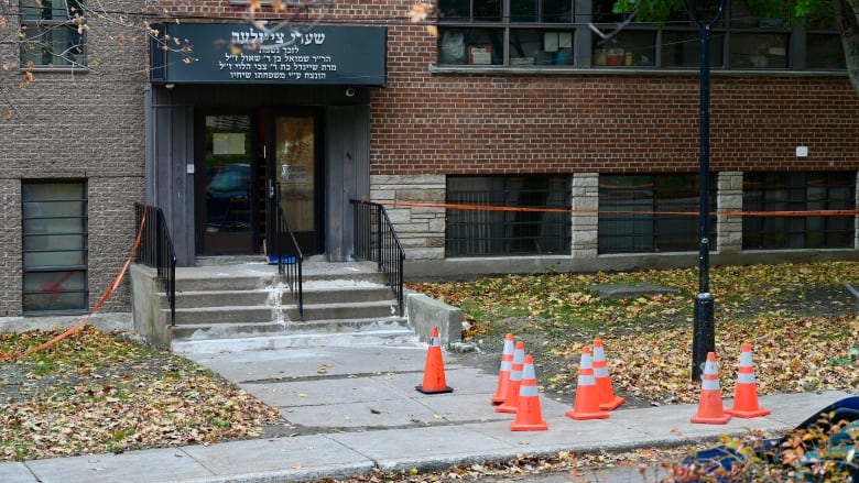 A school building cordoned off by police tape and orange cones. 