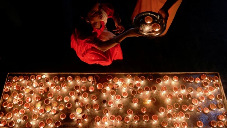 A devotee places lit candles on a surface during a religious ceremony.