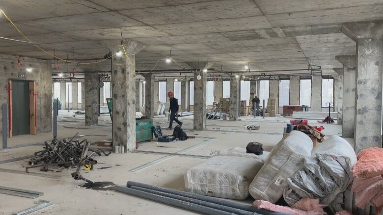 A gutted floor of a high-rise office building. It's an active construction site, people in hard hats are working in the background.