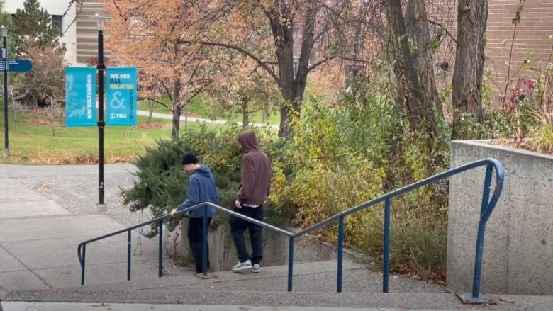 Two students in hoodie walking down a flight of stairs.